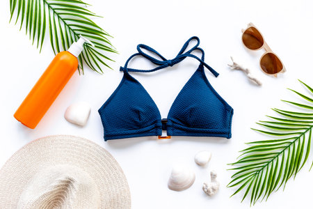 Bikini swimsuit and straw hat with green palm leaves. Summer beach tropical flat lay.