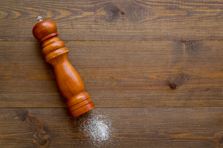 Wooden salt shaker and pile of spilled salt, top view. Cooking concept.の写真素材