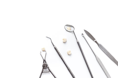 Dental teeth crowns and steel instruments for dental prosthetics, top view. Dentist desk, white background.の写真素材