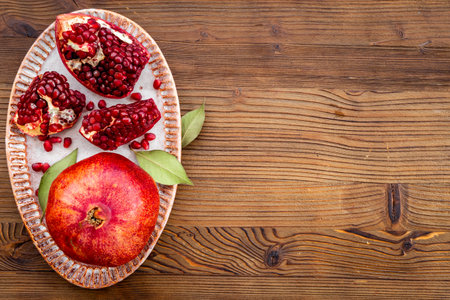 Top view of fresh ripe pomegranate and pieces on plate for eating, top view.の写真素材