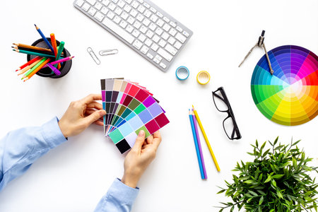 Creative designer hold color paint swatches in hands, top view. Decorator workspace concept.の写真素材