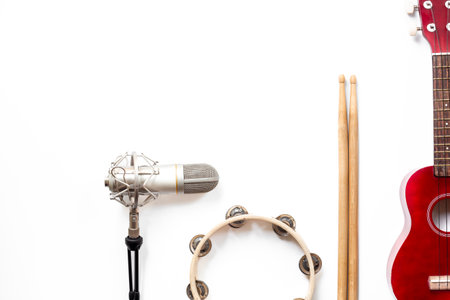Recording music in a studio. Musical instruments for band - small guitar, drumsticks and tambourine - with studio microphone.の写真素材