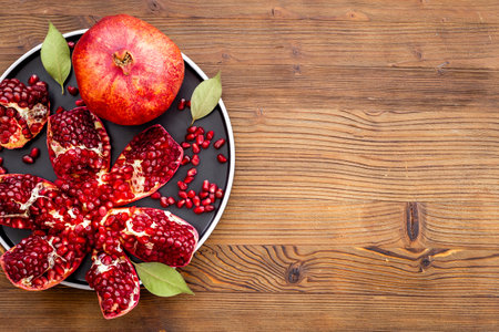 Plate full of fresh ripe pomegranate with cut in half and pieces, top viewの写真素材