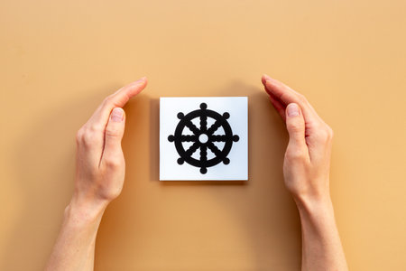 Hands holding Buddhism dharma wheel symbol. World religious concept.の写真素材