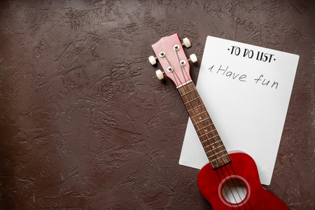 Small guitar ukulele on To do list with words Have fun. Musical instruments, top view.の写真素材