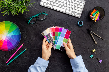 Creative designer hold color paint swatches in hands, top view. Decorator workspace concept.