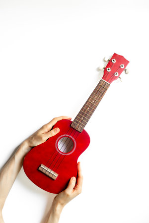 Hand is holding red small guitar ukulele. Musical instrument.の写真素材