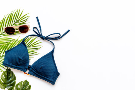 Summer beach tropical flat lay with bikini swimsuit and green leaves, top viewの写真素材