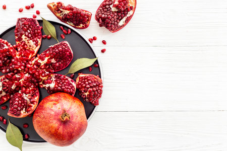 Fresh ripe pomegranate with cut in half and pieces on plate to eat, top view.の写真素材
