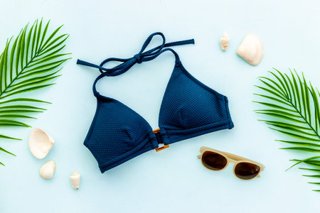 Summer beach tropical flat lay with bikini swimsuit and green leaves, top viewの写真素材