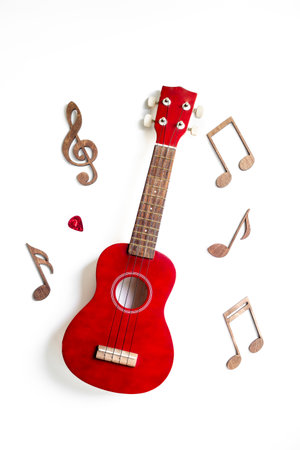 Red small guitar ukulele with musical notes. Musical instruments, top view.の写真素材