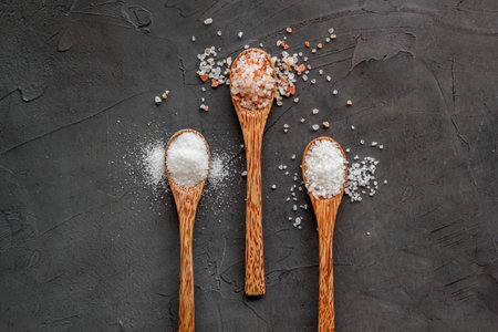 Different kind of sea salt in wooden spoon, top view. Salt for spa, salt baths or cooking.の写真素材