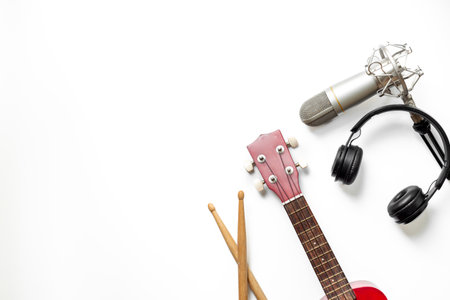 Musical instruments for band - small guitar, drumsticks and tambourine with studio microphone. Recording music in a studio.の写真素材