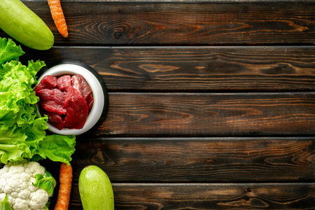 Natural pet food in feeding bowl and ingredients meat and vegetables, top view.の写真素材