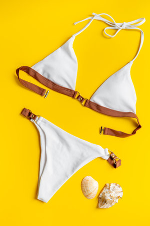 White summer bikini swimsuit on yellow background, top view. Tropical beach concept.の写真素材