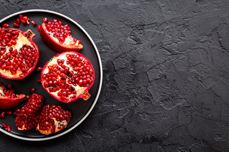 Top view of fresh ripe pomegranate and pieces on plate for eating, top viewの写真素材