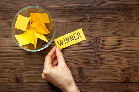 Hand is picking a winner ticket from glass jar, top view. Luck and lottery conceptの写真素材