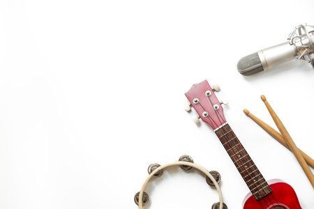 Musical instruments for band - small guitar, drumsticks and tambourine with studio microphone. Recording music in a studio.の写真素材