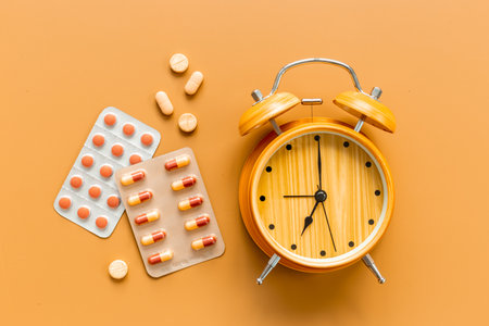 Medical treatment pills and vintage alarm clock, top view. Time to take medicine concept.の写真素材