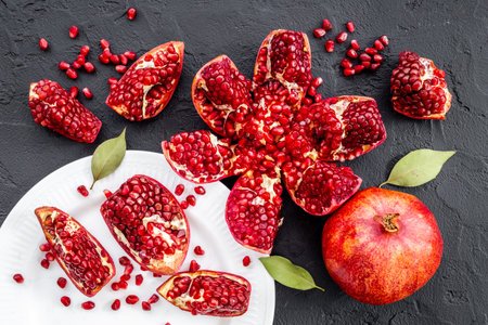 Fresh ripe pomegranate with cut in half and pieces on plate to eat, top viewの写真素材