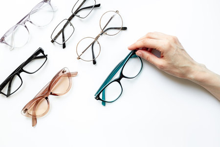 Hand is holding one of many different styles of eyeglasses with lenses on white. Eye care and protection conceptの写真素材