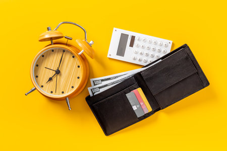 Black wallet with money cash bank card and alarm clock. Time to pay taxes or credit conceptの写真素材