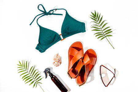 Beach accessories with hard sunlight shadows - bikini swimsuit and tropical leaves, top view.の写真素材