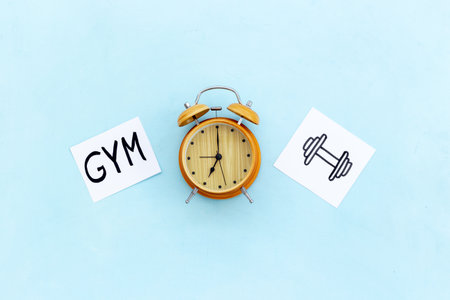 Retro alarm clock with paper cards with hand drawing of sport activities, top view. Time management concept. Life balance and planning conceptの写真素材