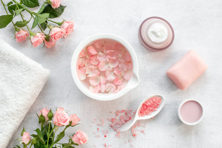 Roses essence water in bowl with petals and skin care cosmetic products with flowers essential oil.の写真素材