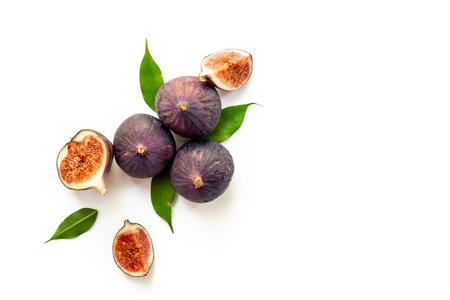 Purple ripe figs fruit and slices with green leaves top view on a white background.の写真素材