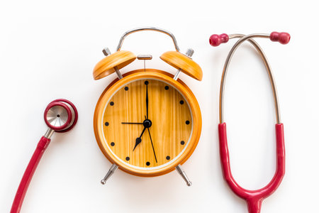 Stethoscope and vintage alarm clock, top view. Time for medical checkup.