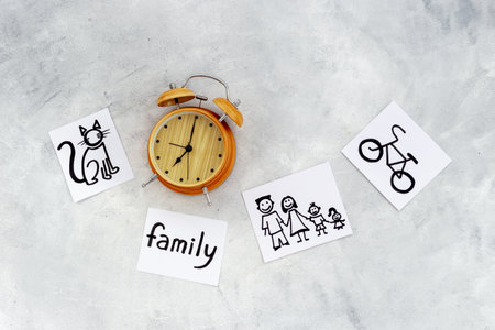 Retro alarm clock and many paper cards with hand drawing of different life activities, top view. Time management concept. Life balance and planning conceptの写真素材