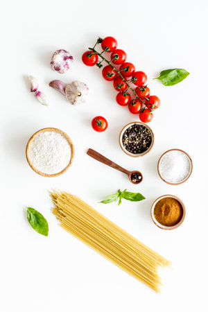 Flat lay of uncooked spaghetti with ingredients for cooking Italian pasta - tomatoes and basil with...