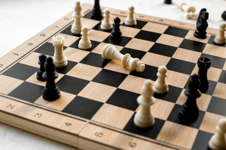 White chess king laying down on chessboard after checkmate.