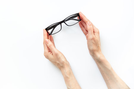 Hand is holding stylish eyeglasses with lenses on white. Eye care and protection concept.の写真素材