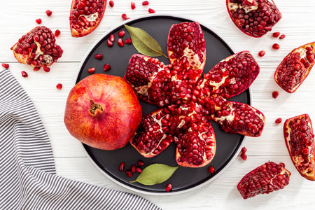 Fresh ripe pomegranate with cut in half and pieces on plate to eat, top viewの写真素材