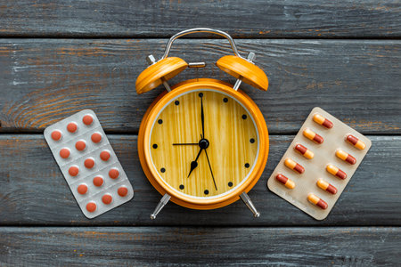 Medical treatment pills and vintage alarm clock, top view. Time to take medicine concept.