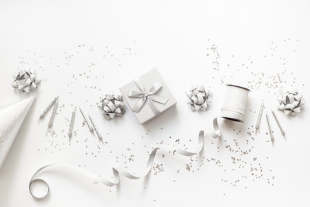 Festive party decoration in silver color with gift box and carnaval caps on white background, top view.の写真素材