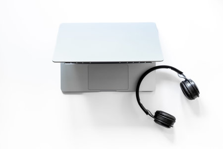 Top view of white business office desk with laptop and headphones.