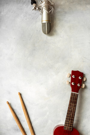 Recording music in a studio. Musical instruments for band - small guitar, drumsticks and tambourine - with studio microphoneの写真素材