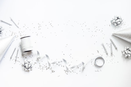 Holiday festive party flat lay with silver carnaval caps and cake candles, top view. Gift box and streamers on white background.の写真素材