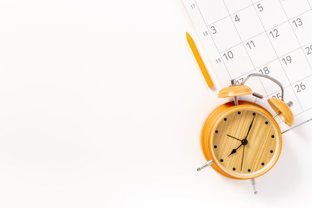 Alarm clock is on calendar with pencil, top view. Planning and time management concept.の写真素材