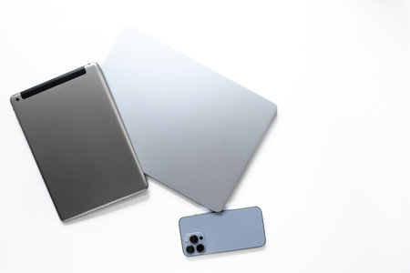 Silver laptop with tablet and mobile phone - high tech gadgets on white background, top view.の写真素材