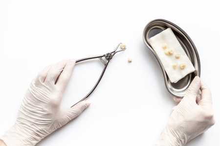 Dentist hand is holding dental equipment tools for teeth care on white background. Professional Dentist desktop, top view.の写真素材