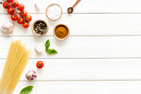 Spaghetti with ingredients for cooking Italian pasta - tomatoes and basil with garlic - on a white wooden background, top view. Flat lay.の写真素材