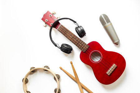 Musical instruments for band - small guitar, drumsticks and tambourine with studio microphone. Recording music in a studio.の写真素材