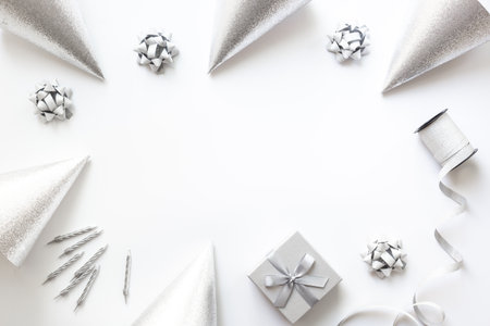 Festive party decoration in silver color with gift box and carnaval caps on white background, top view.の写真素材