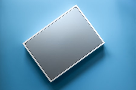 Blue silver laptop in a box on blue background. Unpacking new gadget, top view.の写真素材