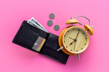 Black wallet with money cash bank card and alarm clock. Time to pay taxes or credit concept.の写真素材