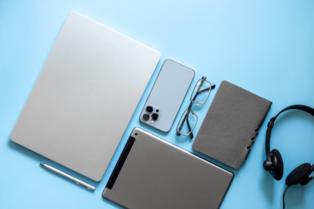 Flat lay of headset and laptop with phone and notebook - customer support equipment at call center, top view. Online conference work space. Online education concept.の写真素材